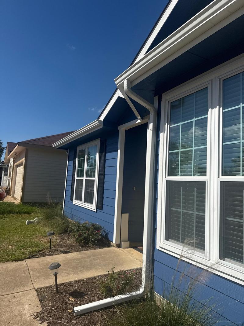 Angled view of a front bay window on a home freshly painted blue with crisp white trim and gutters