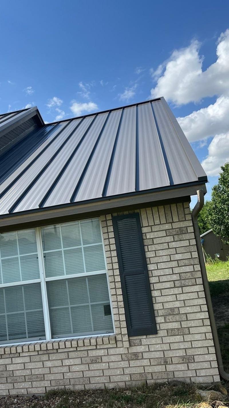 Standing seam metal roof and gable on a tan brick ranch home
