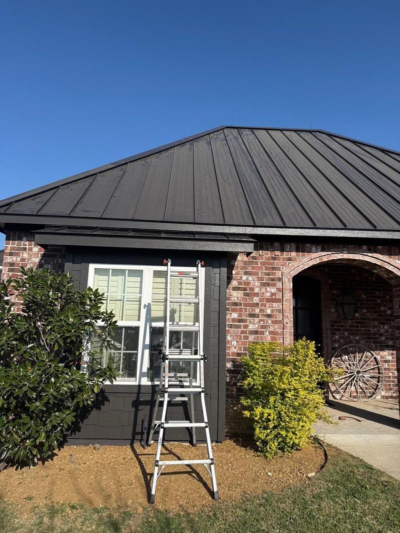 Dark standing seam metal roof over an arched brick entry