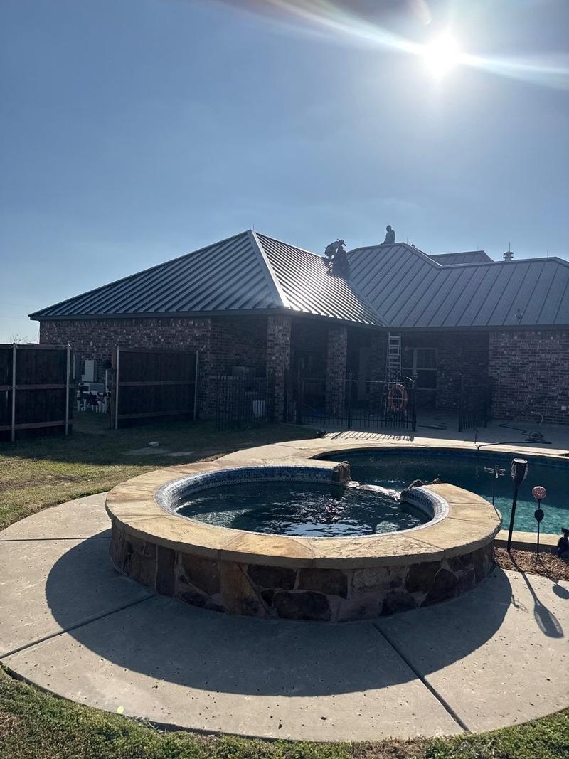 Standing seam metal roof seen from a backyard pool and spa