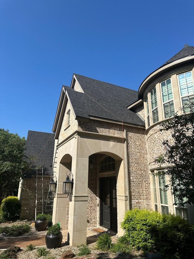 Charcoal architectural shingle roof on a steep two-story brick home in Denton County, TX