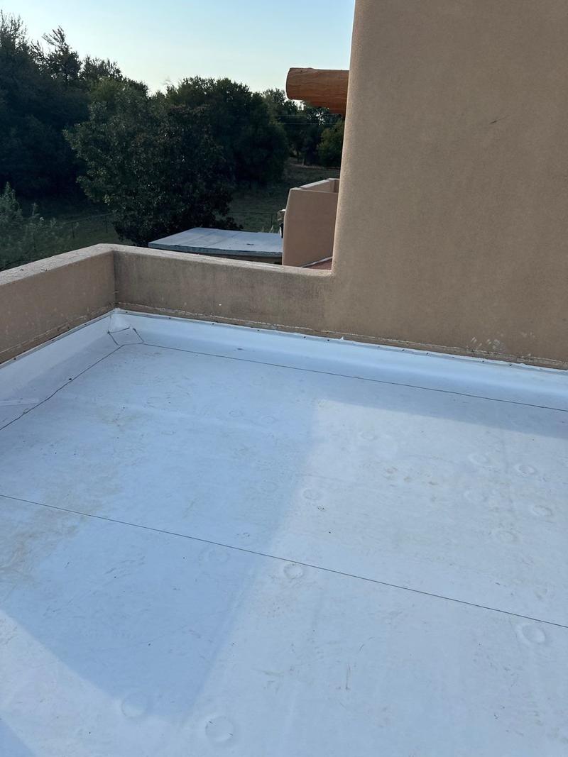New TPO flat roof meeting a raised parapet wall on a pueblo-style home