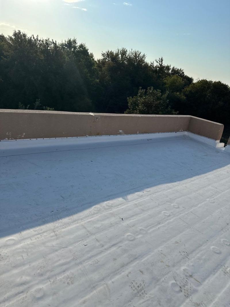 White TPO flat roof with membrane wrapped up the parapet wall